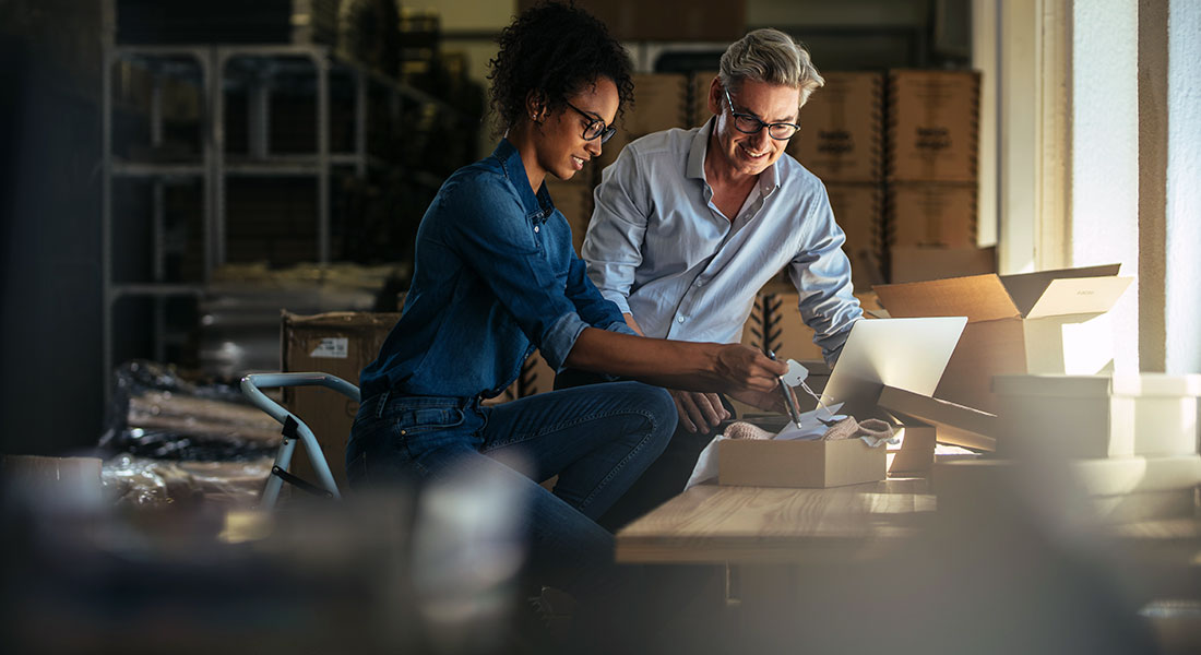 How to get a business loan - photo of a two people looking at a laptop in the warehouse of a small shop